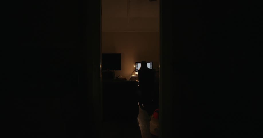 A person working on a computer in a dimly lit room