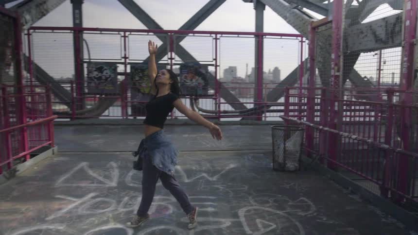 A woman dances around a heavily graffiti covered area
