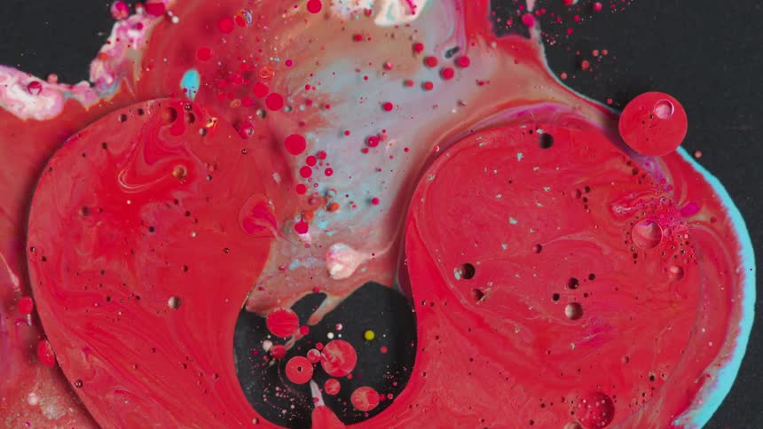 Flowing red and blue paint on a black surface