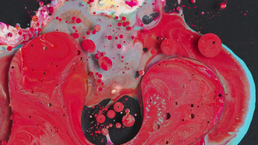 Flowing red and blue paint on a black surface