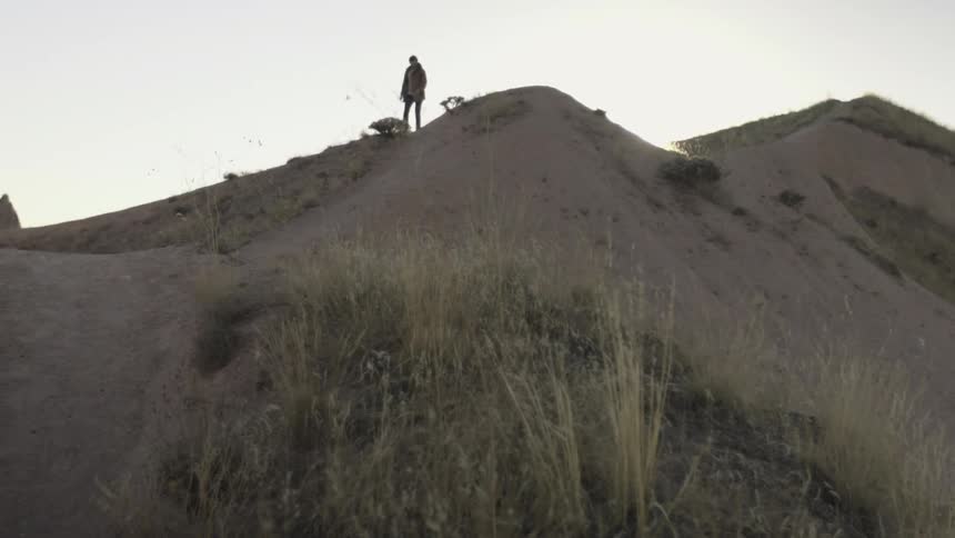 A man stands on a sandy hill