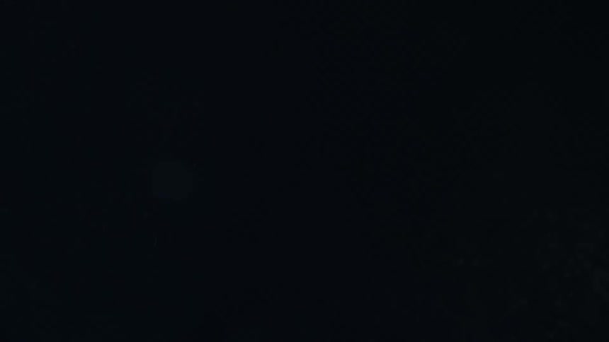 Snow scatters as its blown against a black wall