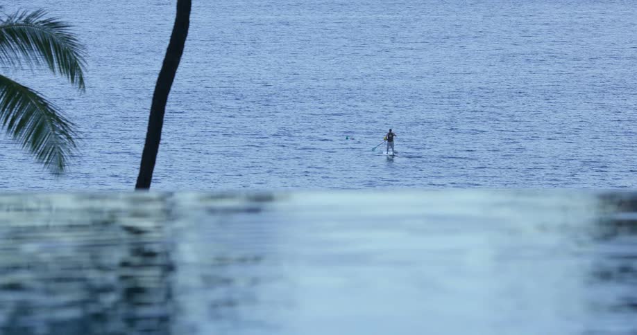 A person in the ocean paddling on a paddle board