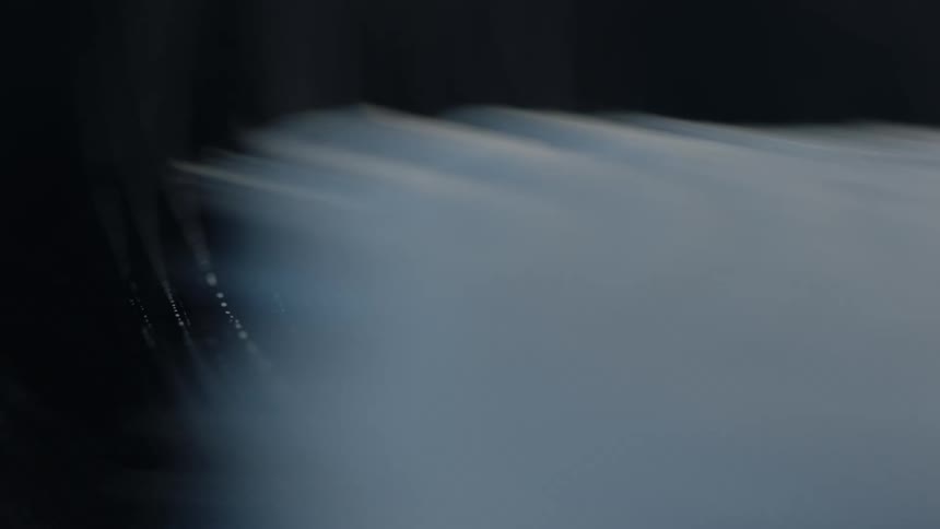 A dark surface is wiped with a cloth and streaks of a cleaning solution are left behind on the surface
