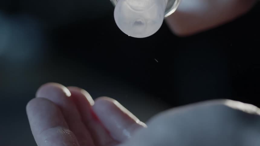 A person with a squeeze bottle squirting liquid on their hands