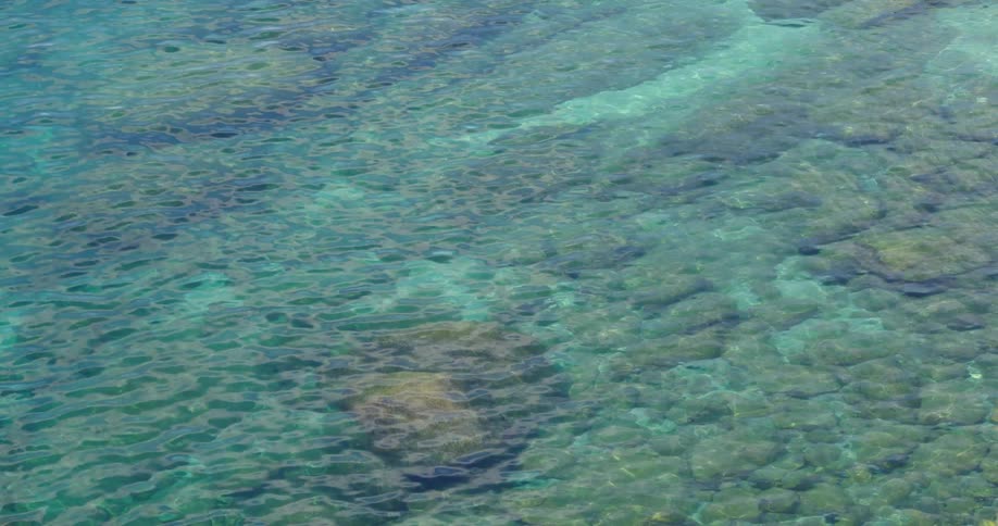 Water with ripples with rocks and sand underneath