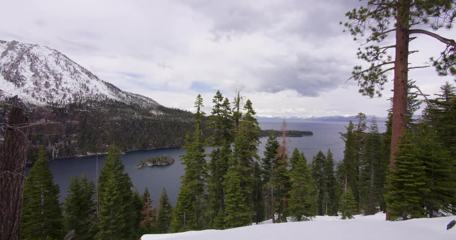 Snow covered mountains in front of a lake near the forest