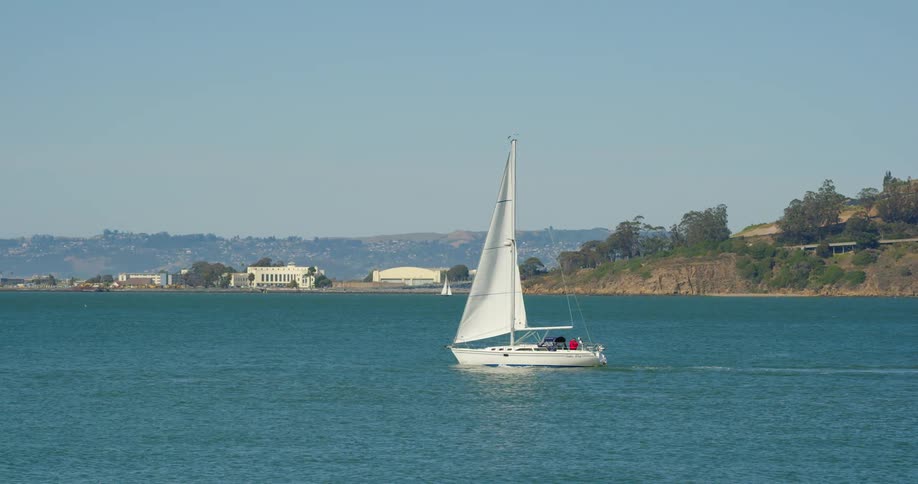 Two people on a sailboat with the skyline in the distance
