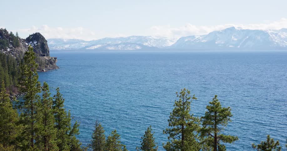 Forest sits across the lake from the snow covered mountains