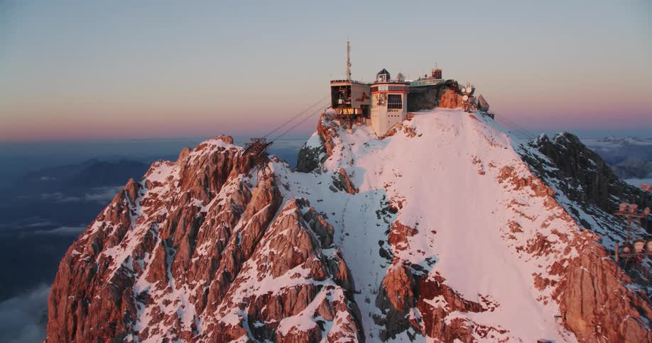 An aerial view of a mountain covered in snow is displayed