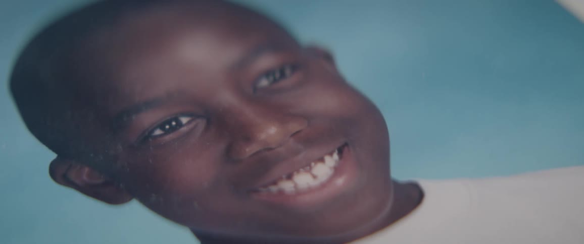 A portrait of a young black boy sits on a surface