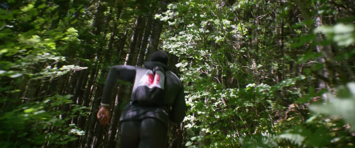 A man wearing a pack runs a forest trail