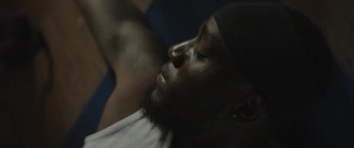 A man in a beanie sleeps on the floor