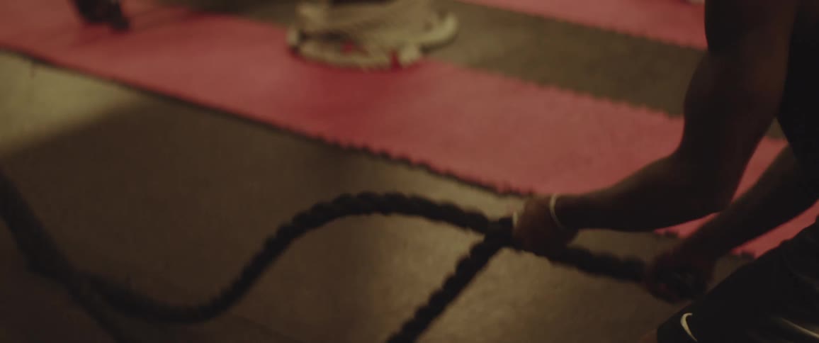 A man works in a gym pulling ropes