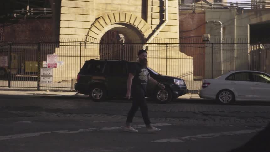 A bearded man watches a woman dance as he walks by