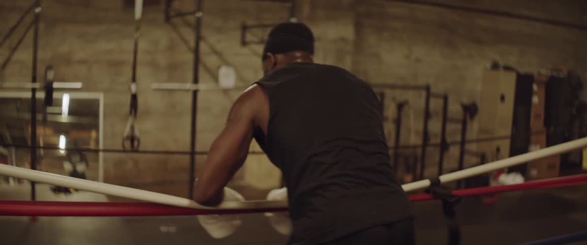 A man is sparring in the ring then takes a rest