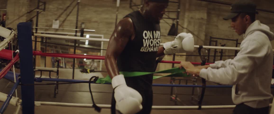 A man places a tension band around a boxer in a ring