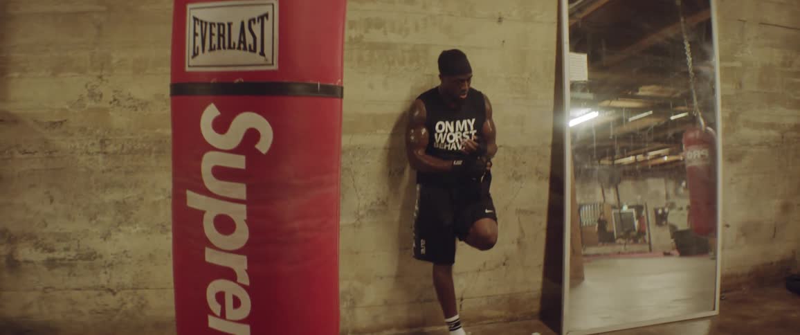 Man leaning against a wall in a gym wrapping his wrists