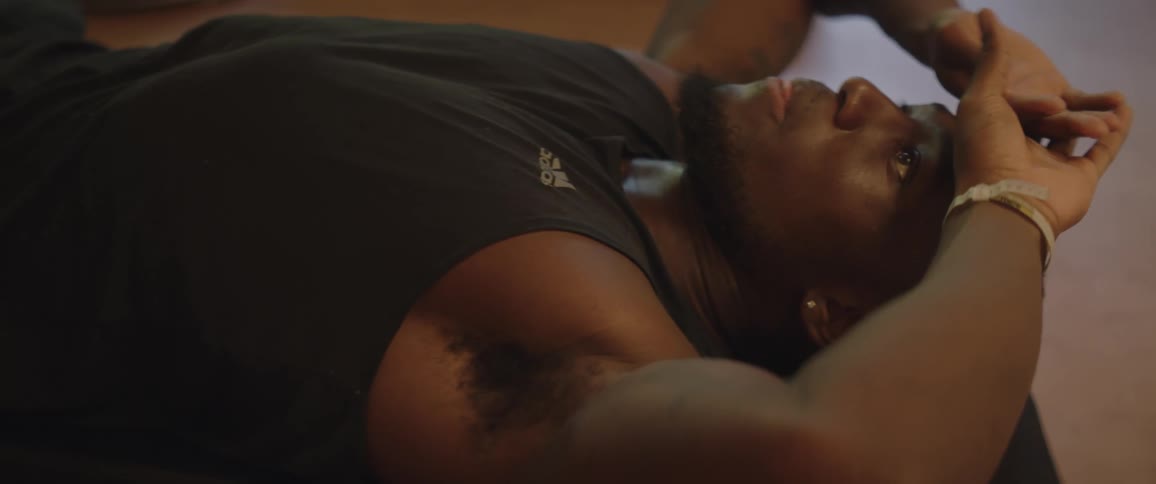 A man lays on the floor of a gym and breathes heavily