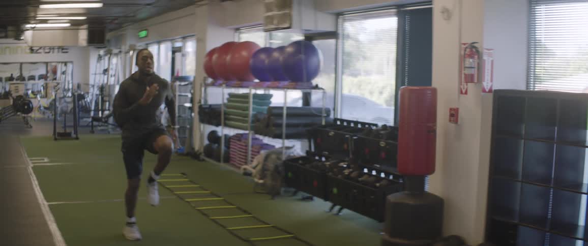 An athlete is lifting his knees as he runs in a gym