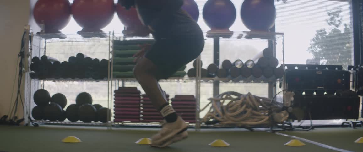 A male athlete is training footwork near shelves full of training equipment