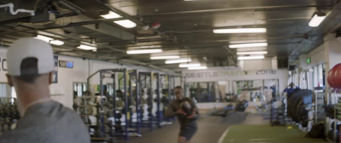 A man runs and catches a football in a weight room