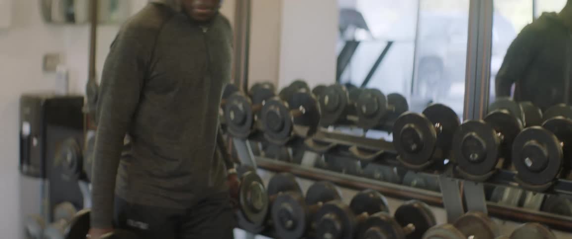 A male athlete chooses some weights and then sits on a bench