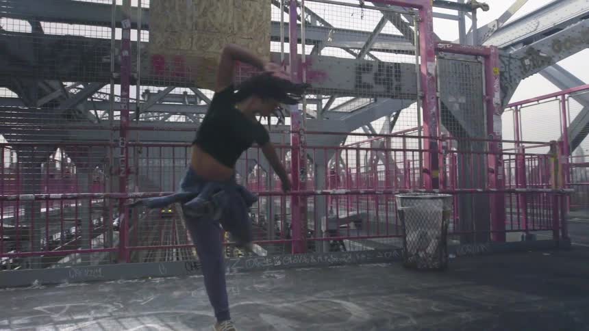 A woman dances near a spray painted metal railing