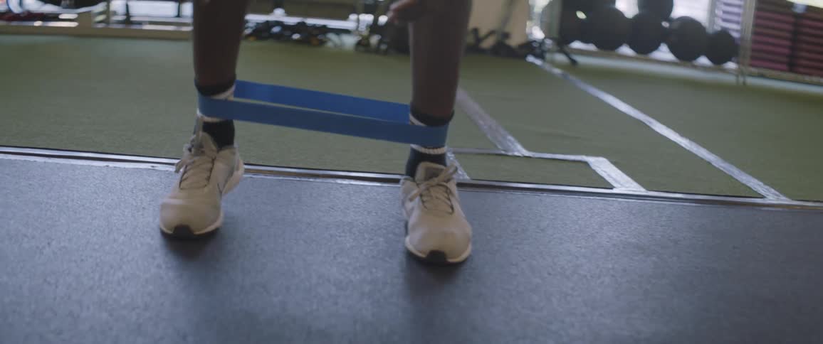 A man performs a footwork exercise with a tension band