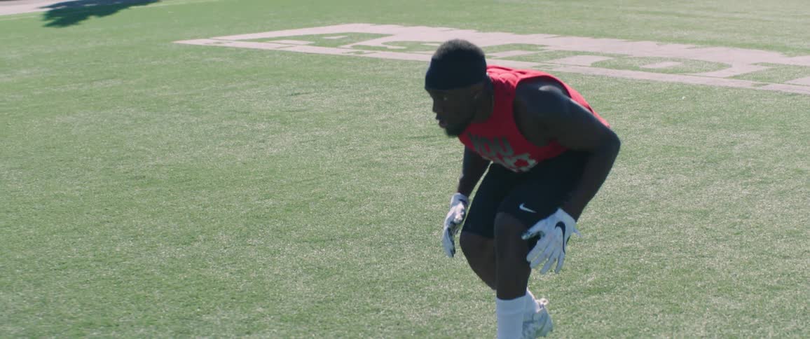 A football player sets and then runs through a drill during a training session