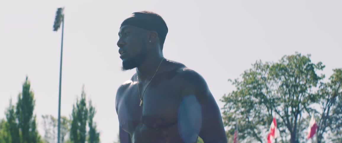 Shirtless man stands breathing outside on a sunny day