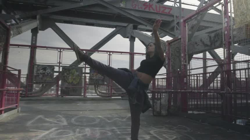Woman dancing and exercising atop a tall building