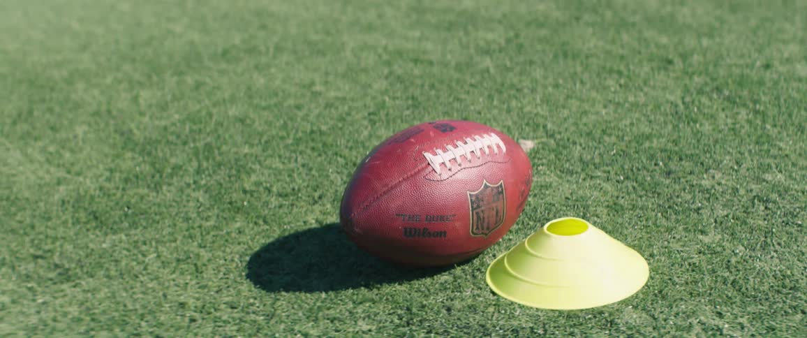 A football is near a cone on the grass