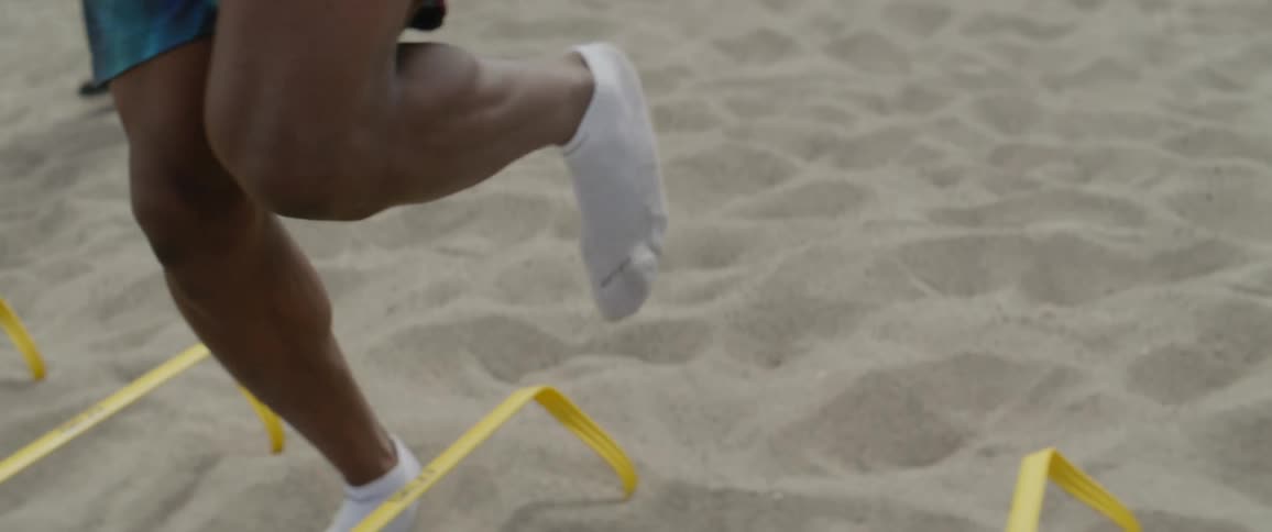 A male athlete is training for strength and agility at the beach