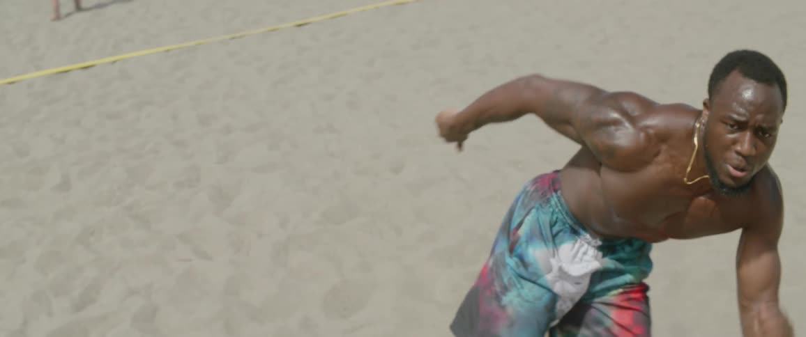 A man runs between orange cones on the beach