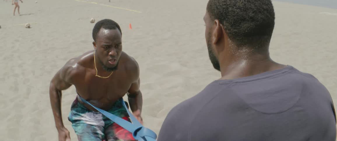 Man exercising on a beach with the aid of a friend