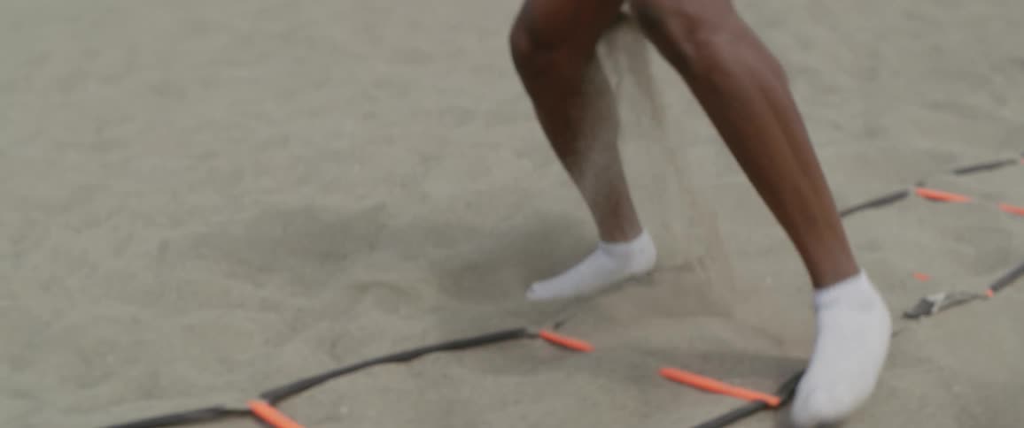 A man in socks exercises on a sandy beach
