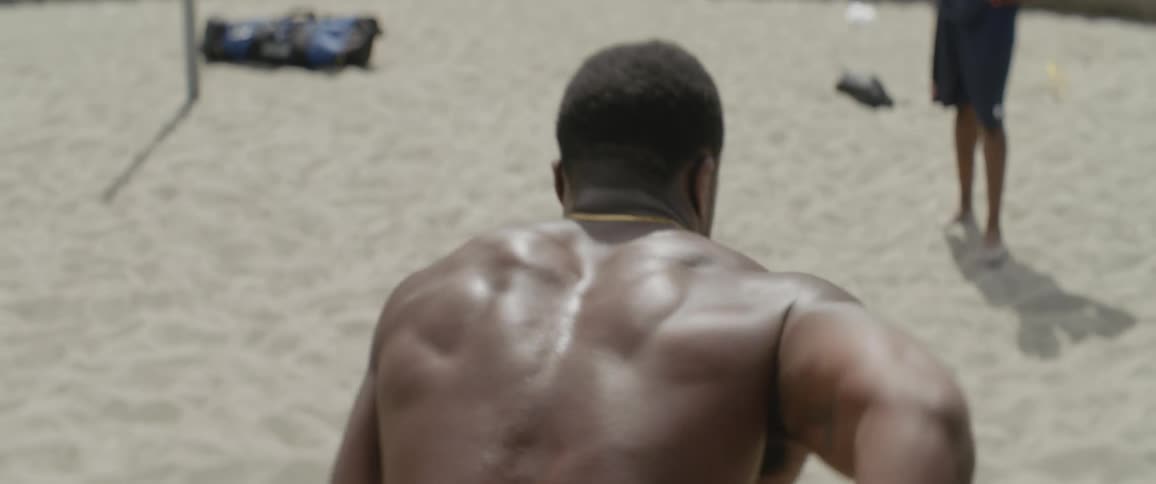 A man runs off pulling something in the sand