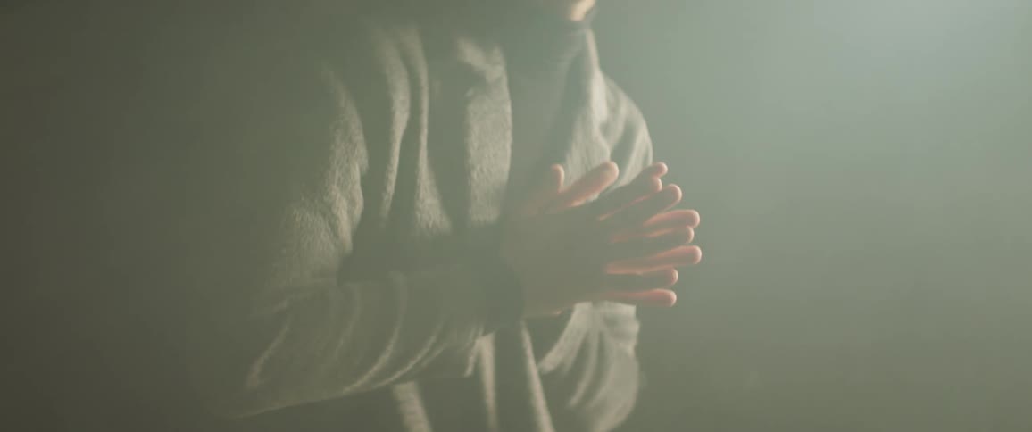 A man rubs his hands together as her stands up and moves