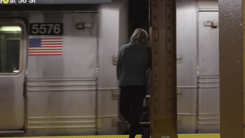 A woman waits for a train car to stop