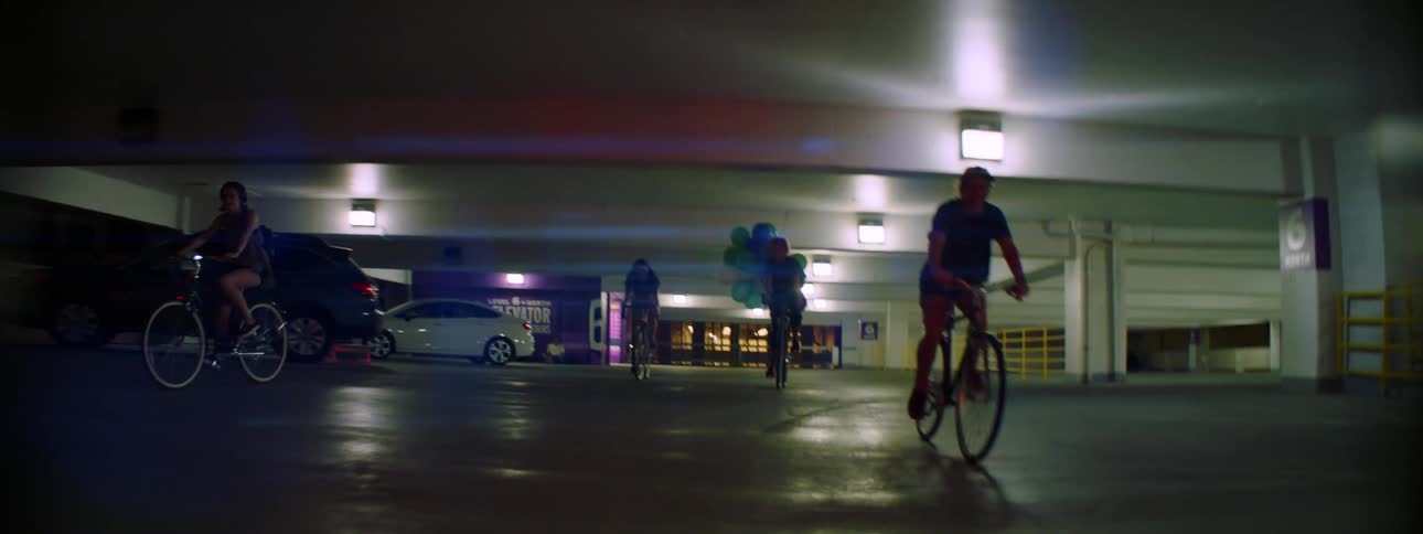 Group of friends have fun riding bicycles inside a parking garage at night