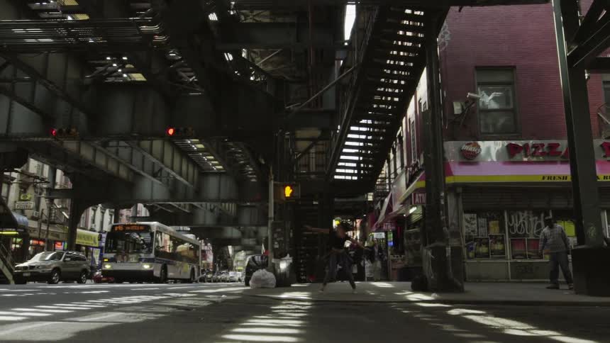 A person dances on the street corner of a large and crowded city