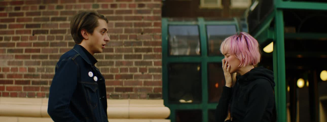 An upset young woman talks irately with a young man before turning and walking away in frustration