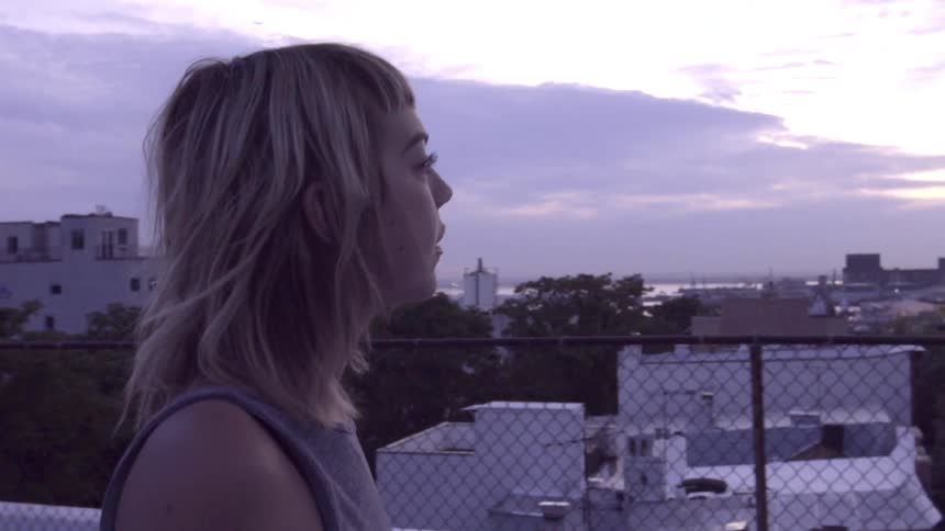 A woman walks out onto a rooftop on a cloudy day