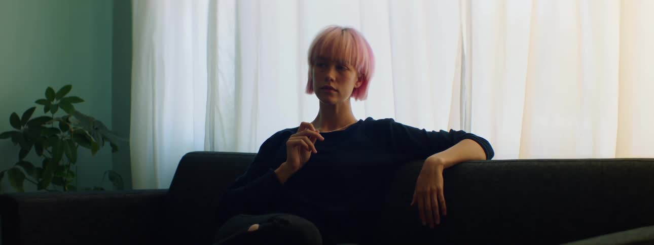 A teenage girl sits at home on a couch playing with her necklace and then it breaks