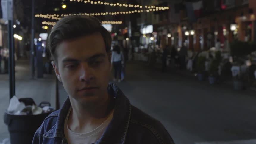 A man looks around as he walks down a street at night
