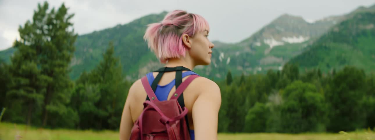 A teenage girl hikes across a field towards the mountains