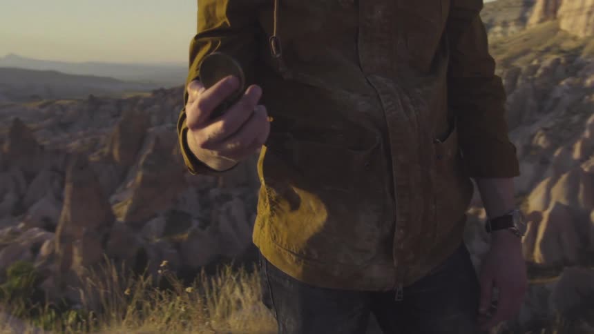 A man standing in a barren landscape with a compass in his hand