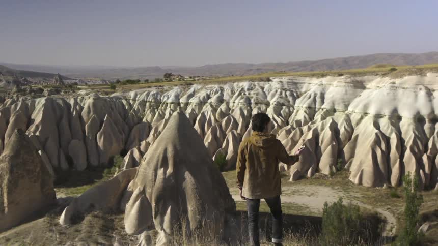 A person stands on a cliff overlooking large rock formations