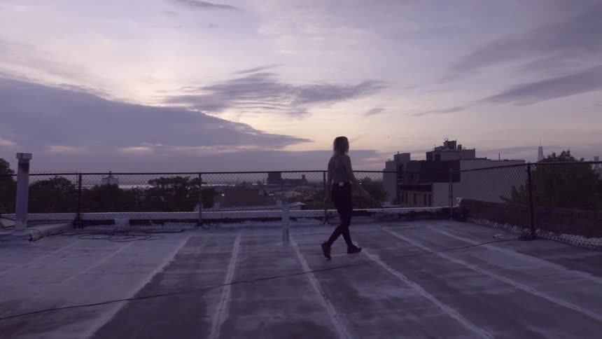 A woman walks on a roof at sunset